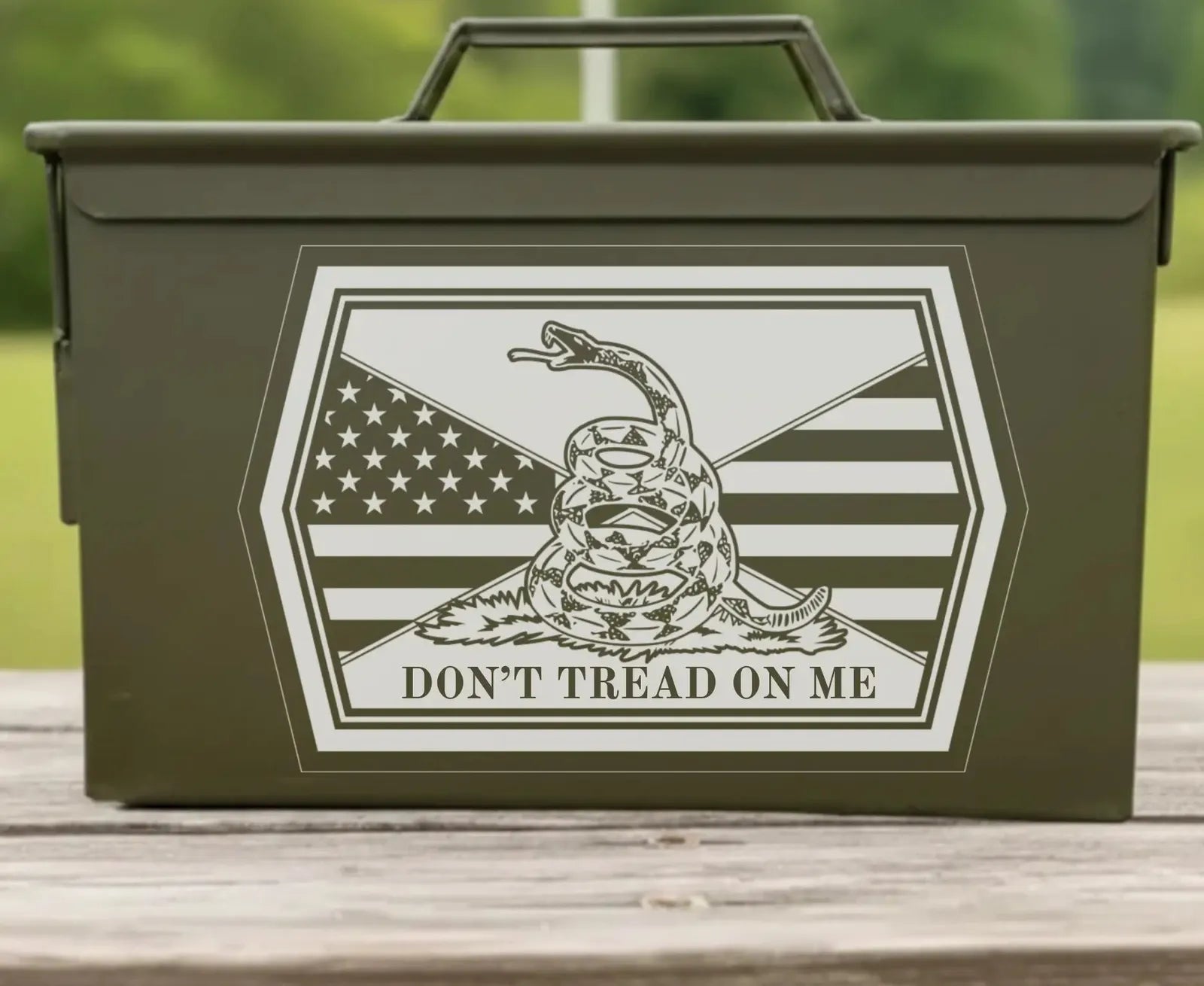 Front of the Don't Tread engraved ammo can: a coiled rattlesnake on grass over the Stars and Stripes, with DON'T TREAD ON ME